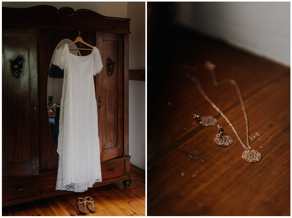 Suknia ślubna koronkowa jest zawieszona na szafie. Obok na zdjęciu widac biżuterie Panny Młodej.